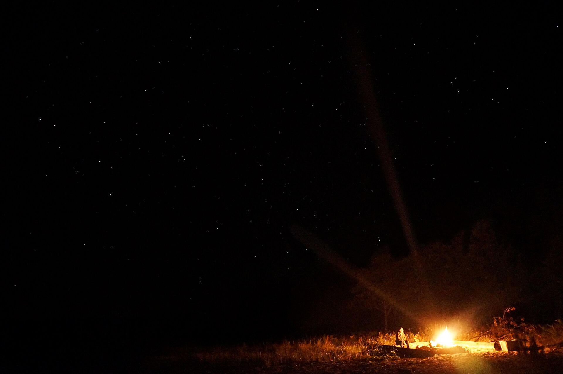 A small campfire glowing beneath a star-filled night sky on Beaver Island, Michigan
