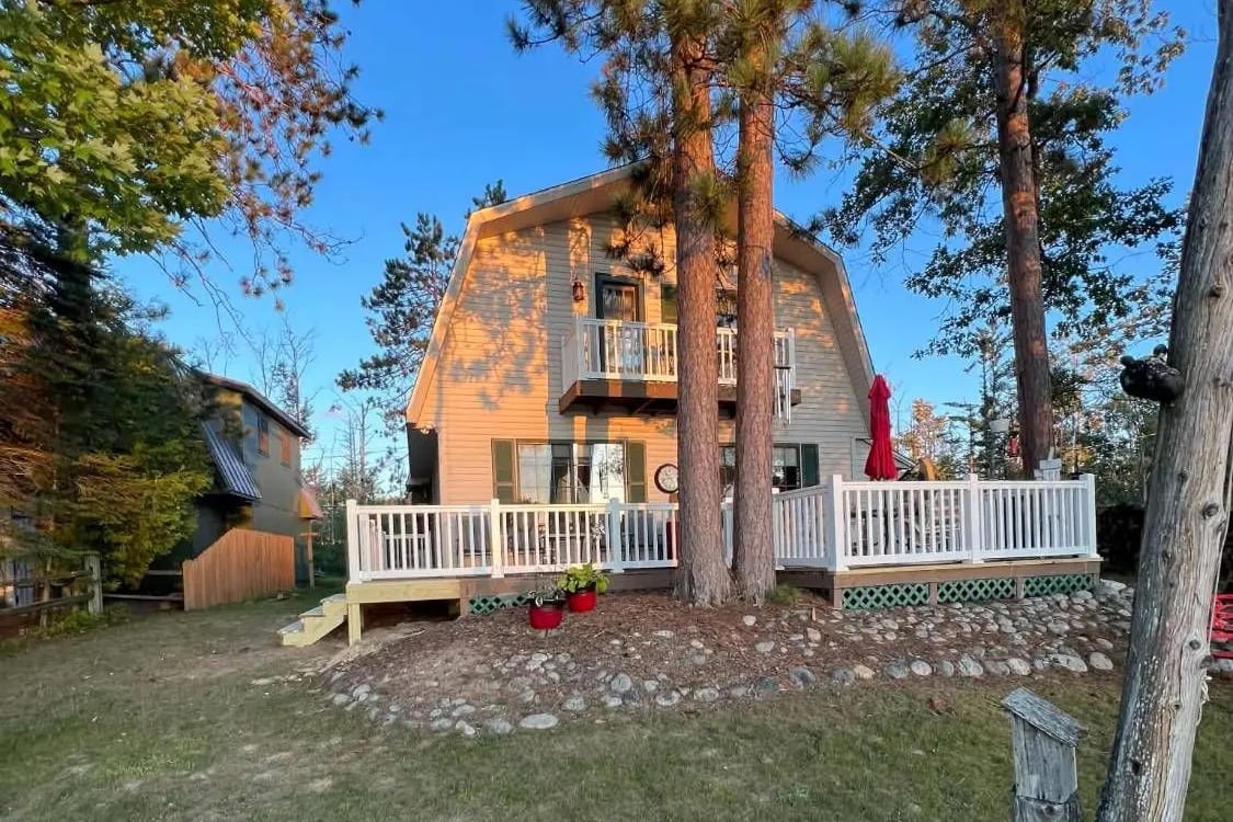 A gambrel-roof lake home with a deck, white vinyl railings and new stairs built by Steve's Handyman Services