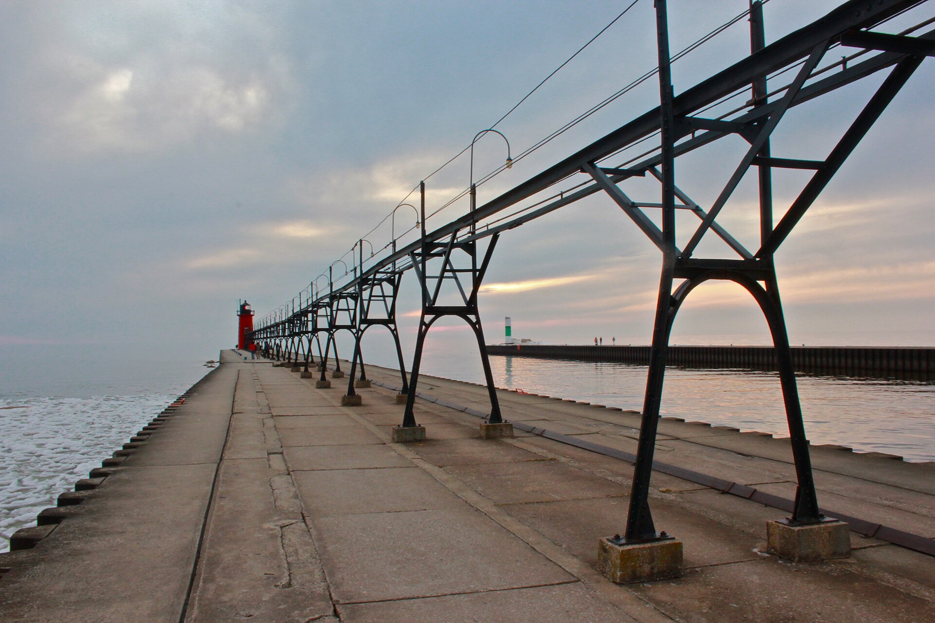 The red South Haven South Pier Lighthouse and its historic catwalk at the mouth of the Black River on Lake Michigan